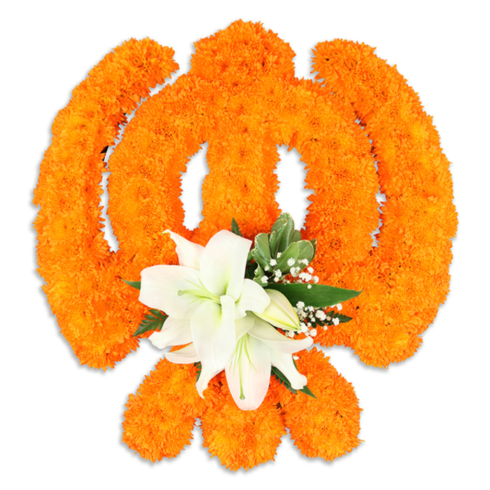 A richly textured floral Ik Onkar symbol occupies the center of a spotless white field, every curve and mark formed from thousands of bright orange marigold blooms carefully nested together to define the emblem that proclaims 'God is One'. The numeral-like strokes, the gentle crescented extensions, and the small bindi are all readable thanks to the dense, uniform marigold surface that catches light and reveals subtle shadowing along its contours. Nestled at the base of the orange formation is a refined accent cluster of white lilies-at least two prominent blooms unfurling with creamy-white petals and visible yellow-green stamens-whose serene presence tempers the marigolds' celebratory energy. Glossy green foliage frames the lilies and tiny white filler flowers, likely baby's breath, drift through the lower composition to add air and softness. A soft drop shadow under the piece suggests it is a physical, freestanding display crafted for reverent presentation. The scent profile-warm marigold earthiness paired with the cool, sweet perfume of lilies-adds a sensory layer that complements the visual symbolism. As a locally made piece from Stanmore, this floral Ik Onkar would be fitting for community Gurdwara tables, home altars, or festival decorations near Stanmore Broadway, Canons Park, or at gatherings marking Vaisakhi and Guru Nanak Jayanti, where devotion, unity, and floral tradition meet in careful, respectful design.