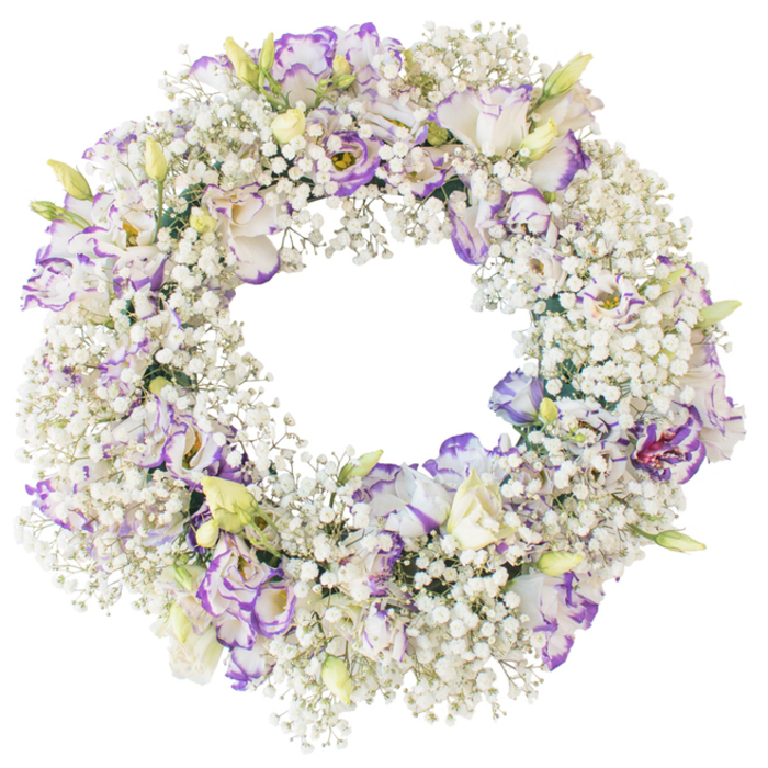 This image shows a tender circular wreath designed as a sympathy tribute, photographed against a pure white background that makes every bloom stand out. The ring is lushly packed with Baby's Breath, the mass of tiny white flowers creating a thick, cushiony layer that looks feather-light yet abundant. Sprinkled throughout this cloud of white are numerous Lisianthus flowers, their slightly ruffled petals giving softness and movement to the design. The Lisianthus petals are predominantly white but are gently outlined and sometimes softly shaded in lavender and purple-violet, adding cool, refined colour without overpowering the calm palette. Some blooms lie fully open, showing layered petals and a hint of darker centre, while others appear as slim buds or newly opening flowers, their tips tinged with pale green and cream. The wreath's form is impeccably round, with a neat, open centre and an even distribution of flowers along the entire circumference so that no section appears heavier or sparser than another. The absence of foliage and decorative elements lets the textures and tones of Gypsophila and Lisianthus carry the whole composition. Under the even, shadow-free lighting, the whites look crisp and clean while the purples remain soft and cool, creating a peaceful atmosphere. This classic wreath would feel at home at a funeral in Stanmore, placed beside a casket, on a stand near the altar, or by a memorial table, its gentle colours and airy structure offering solace. The arrangement suggests a message of peace, remembrance, and lasting affection, carefully composed by a local florist familiar with the needs of grieving families in the area.