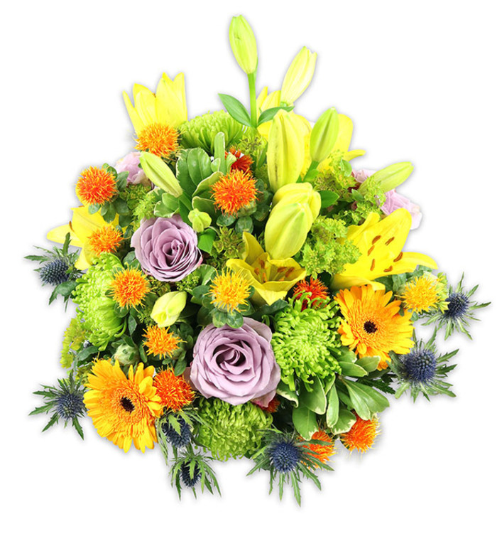 Presented against a stark white studio background, this densely layered bouquet reads as an expertly balanced study of warm tones and surprising cool accents. Several yellow Asiatic lilies are prominent-some open wide with speckled, satiny petals and prismatic stamens, others elongated in pale chartreuse buds that add graceful height. Soft lavender-purple roses offer a romantic, calming centre, their spiralled petals contrasting with the bold, sunny faces of orange Gerbera daisies scattered throughout. A generous framework of lime green button chrysanthemums provides a ruffled, almost mosslike cushioning that makes the arrangement feel abundant and tactile. Interspersed are small, globe-shaped orange and yellow blooms-Craspedia-style accents or similar-that introduce playful, pointillist pops of colour. Blue-grey sea thistles (Eryngium) emerge from the lower sides with spiky, star-like bracts; their cool, steely tones create an elegant counterpoint to the predominantly warm palette and lend a slightly rustic, botanical edge. Various green leaves-broad lily foliage, glossy fillers and slender stems-frame the bouquet and give it depth and movement. Under soft studio lighting the textures-from the lilies' smooth skins to the chrysanthemums' feathery tufts-are clearly defined, inviting touch and close appreciation. This arrangement, ideal for celebrations, thank-yous, or a thoughtful sympathy gift, is the kind of floral work we craft for neighbours across Stanmore and nearby streets like Stanmore Hill and Marsh Lane; Flower Delivery Stanmore can arrange local delivery so the bouquet arrives fresh to a mantelpiece or dining table, where its scent and colour will warm any room.