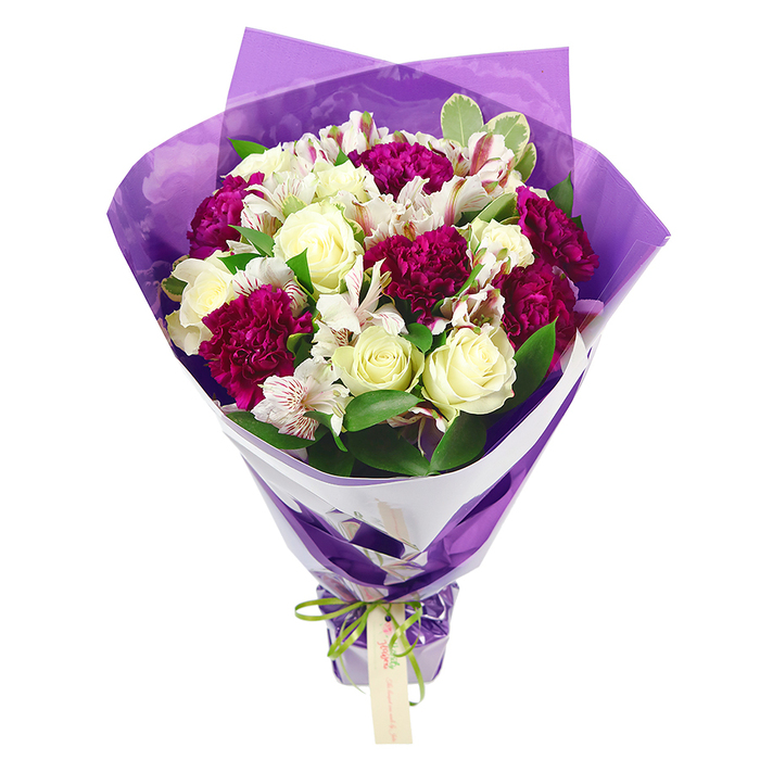 The bouquet in the image is showcased against a plain white background, highlighting the thoughtful craftsmanship and harmonious colour palette that would feel at home in any Stanmore living room. At the top, the flowers are arranged in a rounded, dome-like shape, with velvety magenta carnations taking a leading role. Their tightly packed, frilled petals create a lush, textured surface that immediately draws the eye. Interlaced with these bold blooms are cream-white roses, each one composed of smooth, layered petals that spiral gently from the centre, suggesting a soft, romantic scent and a sense of quiet luxury. Graceful stems of white alstroemeria add a contrasting lightness; their longer petals are decorated with slim streaks of pink-red and framed around dark stamens, giving each flower a slightly wild, hand-painted appearance. The mix of flowers is cradled by fresh green foliage, including a few gently variegated leaves that add another note of visual interest, reminiscent of the leafy borders and hedges around Stanmore Country Park and local gardens. The stems are drawn tightly together, narrowing beneath the full crown of flowers into a well-defined handle. Around the base of the blooms, a fitted collar of crisp white floral paper provides a bright, uncluttered border, enhancing the shapes and colours of the flowers. Over this sits an outer wrapping of translucent purple cellophane or tissue, its softly crinkled texture catching reflections and lending the bouquet a subtle, celebratory glow. A bright lime-green satin ribbon is tied securely in a neat bow where the stems meet the wrapping, from which a small, rectangular, light brown tag hangs, ready to carry a short, handwritten note. The entire arrangement conveys warmth, joy, and care, making it a beautiful choice for Stanmore flower delivery to mark birthdays, anniversaries, graduations, or to send a simple thinking of you to someone near Belmont Circle.