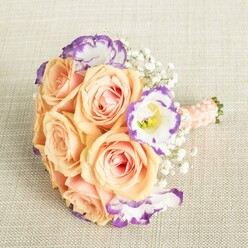 On a softly textured cloth similar to those found in Stanmore's welcoming family homes, this bouquet unfolds-a masterwork where colour and feeling are seamlessly intertwined. Rich peach and apricot roses anchor the arrangement, each petal boasting a creamy blush that suggests both warmth and elegance. Bright lisianthus, with clean white petals softly edged in luminous purple, punctuate the design and catch the eye like wildflowers blooming near Bentley Priory. Wisps of baby's breath are woven skilfully between, adding a featherlight volume and a traditional charm celebrated throughout Stanmore's vibrant community. A perfectly wrapped peach-pink satin ribbon, further adorned with tiny, shimmering pearls, secures the stems and adds a tactile touch of bridal refinement. The overall impression is romantic and uplifting, making it a fitting accessory for a bridesmaid's ensemble during a local ceremony or an inspired centrepiece for a celebration along Stanmore Broadway. The fresh scent, cohesive palette, and attentive craftsmanship speak of the years of experience found among Stanmore florists, and embody the joy and thoughtfulness poured into every life event marked in the area.