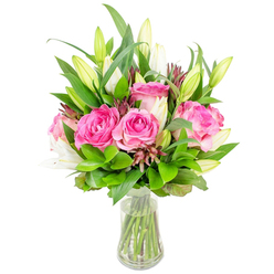 Imagine holding an expertly arranged bouquet from a local Stanmore florist: large, fully opened pink roses form the heart of the design, their velvety petals ranging from soft blush to deep fuchsia and turning gently outwards like layered silk. Interlaced through those roses are tall white lily buds-some closed like small promises, others beginning to unfurl their trumpet shapes-offering a cooling contrast in colour and a subtle, powdery fragrance that balances the roses' sweeter notes. The composition is grounded by abundant green foliage, from broad glossy leaves that reflect a soft sheen to delicate, lighter-green sprigs that create air and lift between blooms. Small, darker burgundy and reddish-brown accents are tucked in to add dimensional shadows and visual punctuation, making the pinks and whites read more vivid against the clean white background. The bouquet is presented in a simple clear glass vase with a slightly tapered base; through the transparent water you can see the straight, freshly cut stems arranged with care. Light skims the petals and leaves, creating soft highlights that suggest a crisp morning light filtering through a Stanmore kitchen window near Stanmore Broadway or Canons Park. This arrangement evokes celebration and quiet elegance-ideal for birthdays, anniversary tables, or as a bright, thoughtful delivery across Stanmore and nearby Harrow. As a florist with local experience, I picture this bouquet bringing immediate cheer to a home after a short local delivery from Flower Delivery Stanmore, while still feeling hand-crafted and personal.