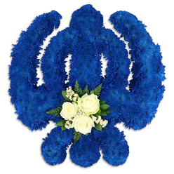 A beautifully sculpted Sikh Khanda flower arrangement is shown in full, resting against a clean white backdrop that allows its shape and colours to stand out with striking clarity. The entire Khanda - the upright central blade, the encircling ring, and the two protective side swords - has been meticulously created from countless royal blue chrysanthemums or similar button-shaped blooms. Their petals form a dense, cushion-like texture, and the uniform deep blue hue suggests thoughtful, deliberate placement by a skilled florist familiar with the importance of Sikh symbols for families in Stanmore and along Marsh Lane or Uxbridge Road. The blue carries a calm, contemplative feeling, well suited to funeral services, remembrance gatherings, or anniversary prayers. Positioned near the base of the central sword is a small but radiant cluster of white flowers. Three elegant white roses, their centres just beginning to open, sit closely together as if in quiet conversation. They are encircled by delicate sprays of baby's breath and touches of dark green foliage, offering a gentle contrast of colour and texture. The white suggests innocence and peace, while the greens echo the nearby greenery of Stanmore Country Park, bringing a sense of the outdoors into this symbolic tribute. Soft shadows beneath the Khanda and along its curves give the impression of depth, making the arrangement appear solid and sculptural rather than flat. The overall effect is one of reverent beauty: a floral Khanda that speaks of faith, dignity, and lasting remembrance, perfectly suited to be delivered to a local gurdwara, funeral home, or family residence in Stanmore.
