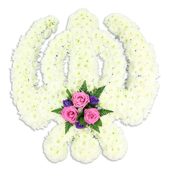 The photograph showcases a striking Sikh Khanda funeral tribute, isolated against a spotless white background that emphasises its clean, sculptural lines. The symbol is entirely built from tightly packed white chrysanthemums, arranged so closely that they form a dense, cushion-like surface with subtle ripples and shadows across the petals. The central double-edged sword rises in a straight, dignified line, encircled by the rounded chakkar, while the two flanking kirpans curve outward with quiet strength, each element carefully defined by the florist's precise shaping. At the very bottom centre, a colourful accent spray offers a gentle visual pause: three pink roses at mid-bloom, their petals soft and velvety, sit amidst a scattering of deep purple florets and a halo of fresh green fern leaves. This touch of pink and purple against the serene white field suggests a balance between grief and gratitude, sorrow and cherished memory. The lighting is bright yet soft, with no harsh shadows, creating a calm, almost peaceful glow around the tribute. With no additional objects or background distractions, the eye is drawn solely to the Khanda and its meaning within Sikh tradition. It is easy to imagine this piece standing near a memorial in Stanmore, perhaps in a quiet chapel or gathering space where families come together after walking from the High Street or nearby residential roads. Suitable for funerals, memorial services, or commemorative events, this floral Khanda expresses respect, faith, and loving remembrance in a way that feels both traditional and deeply personal to the local community.