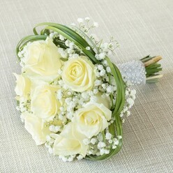 Exuding gentle elegance, this bouquet blends creamy white roses with billowing baby's breath, perfectly suited to the refined yet welcoming ambience of Stanmore gatherings. Each rose is crafted with attention to detail, petals opening in soft spirals from closed bud to blooming perfection, their buttery pigment catching the daylight that drifts through sash windows overlooking Stanmore Country Park. Baby's breath weaves between the blooms, its airy texture conjuring images of misty mornings in local woodlands, tempering the bouquet's lush centre with a touch of whimsical romance. Swathes of verdant bear grass curve in playful loops, framing the flowers and echoing the undulating green edges of Stanmore's leafy avenues. The bouquet is bound with a shimmering silver ribbon, exquisitely finished by hand with rows of dazzling pearls-both a practical and ornamental touch for celebratory occasions. The cut stems, vibrant and alive, hint at the bouquet's freshness and same-day preparation, a signature standard upheld by experienced Stanmore florists. Whether destined for a grand wedding aisle or an intimate anniversary event, this bouquet quietly reflects love, hope, and the timeless artistry found in Stanmore's floral community.