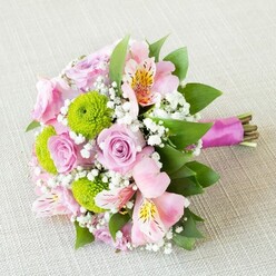This exquisite bouquet, arranged with a florist's intuition and care, brings the spirit of Stanmore's leafy avenues into a single, enchanting composition. Layers of pale lilac-pink roses open in gentle spirals, their fresh petals almost shimmering in the soft daylight-suggestive of quiet Sunday strolls along Marsh Lane. Pink alstroemeria, speckled like the petals of a wildflower found on Bentley Priory Nature Reserve, arc gracefully amidst the central roses, adding dimension and whimsical artistry. Lively green button chrysanthemums nestle between, providing tactile, pom-pom cheerfulness that sets off the pastel hues with a pop of brightness. Wispy clusters of baby's breath impart a light, ethereal air, much like the early mist that drapes Stanmore's wooded corners. Lush, dark green foliage weaves through the bouquet, providing structure akin to the mature oaks lining Stanmore's historic neighborhoods. Bound sympathetically at the stems with a glossy magenta satin ribbon, the bouquet displays a perfect fusion of tradition and freshness, with the natural ends left visible for authenticity and charm. This bouquet, redolent of local gardens and the promise of a new season, feels ideal for weddings held at local venues near Stanmore Golf Club, or for marking personal milestones and celebrations with an eloquent floral gesture made for the heart of Stanmore.