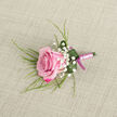 Placed against a neutral, light beige fabric that looks like gently woven linen, this single pink rose boutonniere appears as though it has just been arranged in a quiet corner of a Stanmore flower shop. The rose rests on a slight diagonal in the lower left quadrant of the image, its petals layered in a tight rosette. The colour shifts from an intense magenta along the outer petal edges to a softer, pastel pink at the centre, giving the bloom depth and a sense of tenderness. Around it, delicate sprays of Baby's Breath are tucked neatly into the design, their tiny white blossoms scattered like stars around the rose, adding softness and subtle contrast. Long, fine strands of green foliage stretch from behind the flower, extending in graceful arcs that give the boutonniere a sense of movement and natural ease, reminiscent of greenery in Stanmore Country Park on a still morning. A single broader leaf in deep green curls around the base, its surface dotted with a few clear, bead-like drops of water that catch the soft light. The stems are wrapped in a pale pink satin ribbon wound tightly to form a smooth handle, with a small bow in a deeper pink shade tied at the base, introducing a neat, tailored finish. The light is gentle and evenly diffused, casting only the faintest of shadows and emphasising the textures of petal, leaf, and fabric. Created with care by a local florist, this boutonniere feels perfectly suited to a groom, usher, or prom guest attending a celebration in Stanmore, from local synagogues to elegant venues along The Broadway.