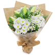 A hand-tied bouquet of pure white blossoms stands upright against a clean white background, the composition balanced and quietly confident. At its heart a generous cluster of daisy-like chrysanthemums forms a soft, luminous dome: each bloom fans dozens of narrow, paper-soft petals from a subtle yellow eye, giving the bouquet a cheerful, classic character. Interwoven through this mass of white are elongated pale green lily buds - some tightly furled, others just beginning to hint at opening - their smooth, slightly striped outer petals promising sculpted blooms in the days to come. Feathery sprays of baby's breath (Gypsophila) float like warm breath between the larger flowers, adding an ethereal, cloud-like texture that softens edges and introduces delicate negative space. Deep, glossy green foliage cups the stems and lifts the white flowers, the leaves' satiny surfaces creating a fresh, garden-fresh contrast that makes the whites feel crisp and alive. The bouquet is wrapped in an inner sheet of natural, crinkled brown kraft paper that lends an earthy, comforting base, then finished with a clear, glossy cellophane layer that catches the studio light and protects the stems without obscuring the arrangement. The wrapping is gathered and tied at the base in a neat, portable bundle, the hand-tie forming a small stand so the bouquet reads as both gift and gesture. There is a restrained fragrance - the soft green note of new stems and a faint powder of chrysanthemum - and an overall mood of calm, sincerity. As a local florist might explain when preparing flowers for delivery around Stanmore Broadway or for visitors leaving flowers at Canons Park, this arrangement suits birthdays, quiet congratulations, or a tender expression of sympathy, offering the timeless language of white blooms.