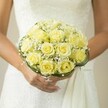 Captured in the soft light that graces Stanmore in the spring, a bridal bouquet gently rests in the bride's hands-a rounded composition of yellow roses whose petals glow with the hope of a new beginning. Between each rose, baby's breath is tucked delicately, each white cluster evoking a light, frosted mist rising over the morning landscape of Stanmore's gardens. At the bouquet's foundation, curls of green grass or slender wire form a stylish circlet, giving the arrangement both balance and quiet sophistication. The scene is set against the flowing lines of a white wedding dress, the fabric's texture softly blurred but suggestive of classic lacework or embroidery popular among local Stanmore brides. The bride's hands cradle the bouquet with care, nails polished in pale nude, a ring gleaming as a token of commitment. Every detail draws the senses to Stanmore's peaceful streets and the allure of bespoke wedding celebrations, making this bouquet a fragrant, visual symbol of love's fresh start in this cherished North London community.