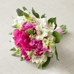 Resting atop a light, subtly textured surface that echoes the quiet sophistication of Stanmore, this hand-tied bouquet is a study in bridal beauty and local pride. Dominated by exuberant hot pink peonies-each bloom unfurling with countless ruffled petals in rich fuchsia-the bouquet exudes luxury and celebration. Nestled among them, flawless white Alstroemeria catch the light, their slender, star-like petals intricately painted with deep, reddish-maroon lines, adding detail and luminous contrast. Spiking upward are clusters of bright green buds, suggesting Veronica or Hyacinth, infusing the bouquet with dynamic freshness and an airy, uplifting mood. Smaller soft, creamy-white flowers delicately weave between larger blossoms, introducing softness and balance, while deep green leafy foliage offers structure and a hint of natural serenity. Binding the base is a glossy pink satin ribbon, ensuring each stem sits perfectly, ready for an elegant Stanmore occasion-perhaps a wedding, garden party, or anniversary gathering. This arrangement is more than a visual delight: it's a reflection of Stanmore's own charm and the skilled touch of its local florists, designed to capture fleeting moments of joy and lifelong memories.