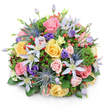 A richly detailed, round bouquet of mixed fresh flowers is displayed against a crisp white background, highlighting the artistry and colour harmony you might expect from a skilled Stanmore florist. The bouquet forms a generous dome, filled with lush garden roses in shades of blush pink, mellow yellow, and gentle peach. Some roses are fully open, their petals swirling in layered spirals, while others remain softly closed, adding a sense of unfolding stories and tender emotion. Between these classic blooms, star-shaped clematis in white and pale lavender stretch their slender petals around bright yellow centres, lending a light, slightly whimsical feel that echoes the relaxed charm of gardens near Stanmore Country Park. Standing out among the softness, stems of blue eryngium, or sea holly, present metallic blue-grey, spiky heads and bracts, adding bold, tactile contrast and a distinctive, modern twist. Purple lisianthus blooms are tucked throughout the arrangement, from tight, promising buds to open, ruffled flowers, deepening the colour palette and creating gentle pockets of shadow. Scattered clusters of glossy red hypericum berries punctuate the bouquet with playful bursts of colour and rounded, bead-like texture. The entire design is encircled by a rich assortment of greenery: broad, shiny leaves, fine, feathery sprigs, and touches of darker, burgundy-tinted foliage work together to frame the flowers and enhance their vibrancy. Soft, even lighting ensures each element is clearly visible, with only a faint shadow marking the base. The bouquet exudes warmth, gratitude, and thoughtful celebration, making it an ideal choice for birthdays, anniversaries, or heartfelt condolences delivered by Flower Delivery Stanmore to homes and offices around Stanmore Hill, Canons Park, and the wider HA7 community.
