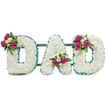 A dignified three-dimensional tribute spells the word DAD in large, capital letters, each letter formed from a dense carpet of pristine white chrysanthemums that create a soft, cushion-like surface against a pure white backdrop. The tiny blooms are packed closely so the letters read as cloud-white blocks, their rounded petals catching a cool, diffuse light that suggests a quiet morning in Stanmore. A ruffled, emerald-green ribbon traces both the outer and inner edges of each character, its pleated texture adding crisp definition and a steady, respectful contrast to the white mass of flowers. Behind the letters a subtle dark green or grey horizontal bar supports the piece, hinting at the solid easel or stand used for graveside or chapel display.

Carefully balanced accent clusters punctuate each letter: the first D carries a spray of rich magenta roses and small white freesias on its upper left curve; the A has its cluster nestled gracefully in the lower V; the final D mirrors the first with a matching arrangement on its upper right. The roses offer a warm, velvety note while the freesia brings a delicate, honeyed scent, and deep green foliage gives depth and structure. The overall feeling is one of reverent tenderness-traditional and personal-a floral voice for goodbye. A local florist from Stanmore might imagine this placed beside a polished pew at St. John's or at a graveside near Stanmore Common, where the clean colours and quiet lines feel at once respectful and intimately consoling.