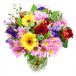 The photograph features a vibrant, mixed-colour bouquet that appears lush and full, arranged in a simple clear glass vase and set before a plain white background. Dominating the centre are rich, dark red roses, their velvety petals tightly layered and gently spiralling outward to create a luxurious, romantic focus. Beside them, yellow gerbera daisies with dark brown-orange centres offer a bright contrast, their neat, radiating petals bringing a joyful, sunlit energy akin to a bright morning over Stanmore's rooftops. Surrounding these key blooms is an abundant ring of pink and soft lavender chrysanthemums or daisies, each small flower composed of fine petals and a yellow core, building a soft, cushiony texture and generous volume. Threaded between these are elegant stalks of purple and lilac lisianthus, their bell-shaped, slightly frilled flowers adding cool, sophisticated notes and interesting height. Nestled among the petals, glossy red hypericum berries appear in small clusters, adding rounded forms and a polished, contemporary touch. The whole arrangement is woven with varied greenery: broad, darker leaves provide a sturdy base, while lighter, more delicate green sprigs soften the outline and give a sense of movement, like a gentle breeze passing through the trees near Canons Park. Through the sides of the glass vase, you can clearly see the neatly cut stems fanning out into clear water, showing the precision and care taken by the florist. The bouquet feels abundant yet harmonious, perfect for marking special occasions, sending get-well wishes, or simply bringing a touch of fresh, floral colour into everyday life in Stanmore, with reliable local delivery that keeps the flowers looking as fresh as they appear here.