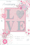 The anniversary card in this image combines romantic artistry with a calm, polished feel that echoes the gentle character of Stanmore. At its centre, the word LOVE appears in bold, raised letters that you can almost feel beneath your fingertips. These letters are coated with a delicate veil of glitter, edged in subtle silver that catches and reflects light the way early morning sun glints on Stanmore's leafy streets. The backdrop is a soft blush pink, creating a warm, affectionate foundation for the design. Framing the central word, a network of stylised blossoms and curling leaves drifts outward. These illustrations are finely drawn, their petals shaded in pale pinks and whites with touches of silvery grey, giving the impression of a light, airy bouquet translated into line art. The vines and swirls interlace gently, echoing the curves of the script that carries heartfelt anniversary messages across the card. The typography is elegant and flowing, its lines echoing the stems and tendrils that surround it. Despite the intricate detail, the composition feels spacious and uncluttered, thanks to thoughtful use of negative space between floral clusters and text. There is a quiet elegance in how the glitter, colours, and lines come together, suggesting both celebration and long-standing commitment. The card's overall mood is one of tender reflection and joy, much like the feeling of unboxing a carefully chosen anniversary arrangement from a local Stanmore florist, ready to brighten a cherished moment at home.